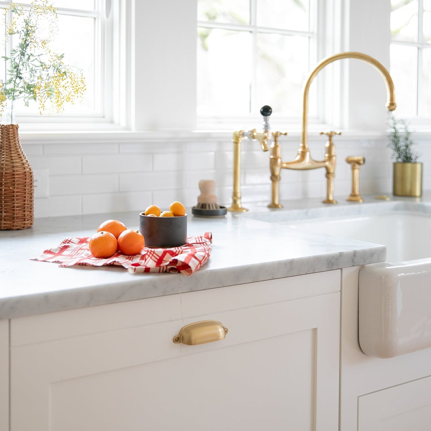 Close view of Brunswick Pull showcasing its solid brass finish and exposed mounting hardware on a white kitchen cabinet