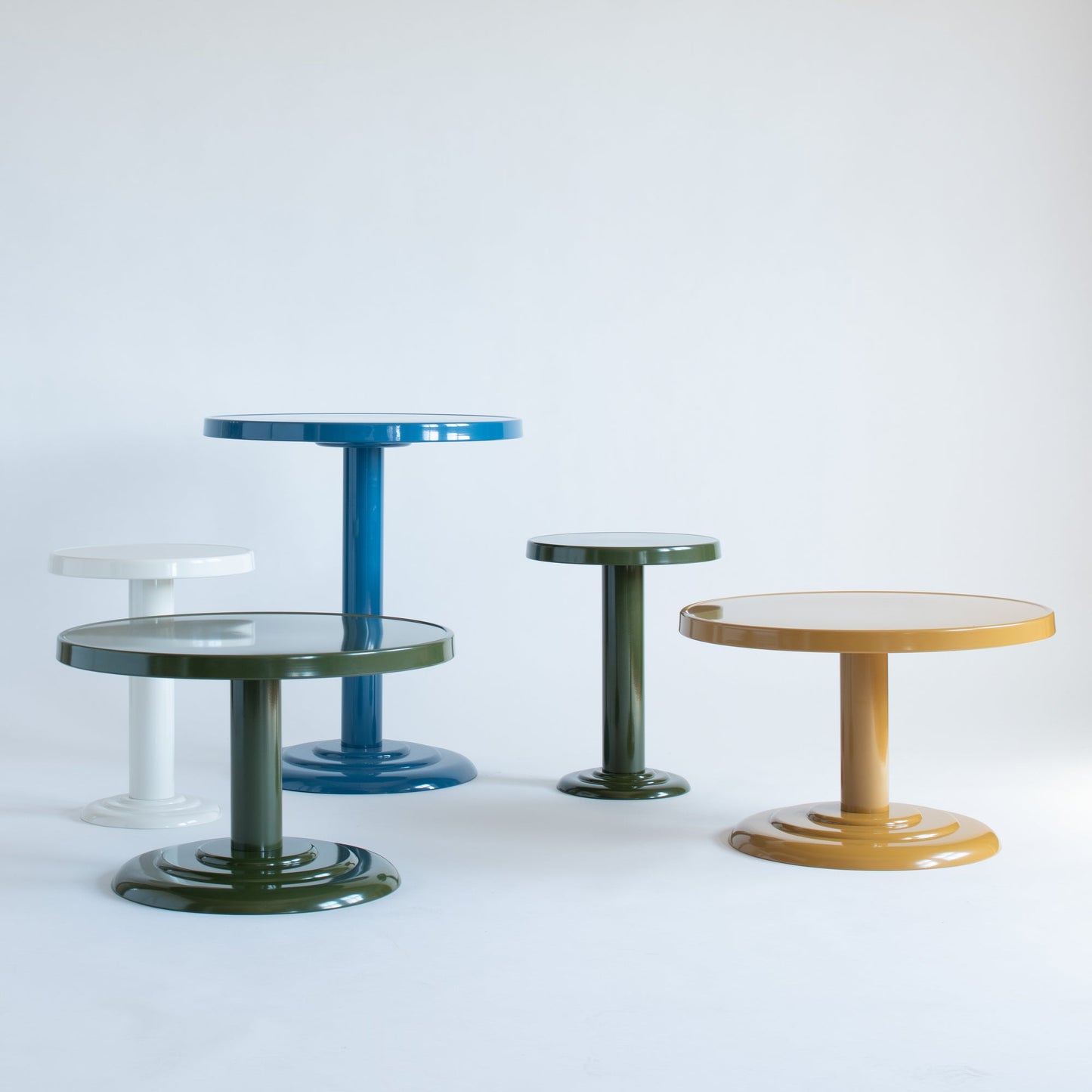 Owen Cocktail Tables at varying heights with glossy steel tops in blue, green and white on white