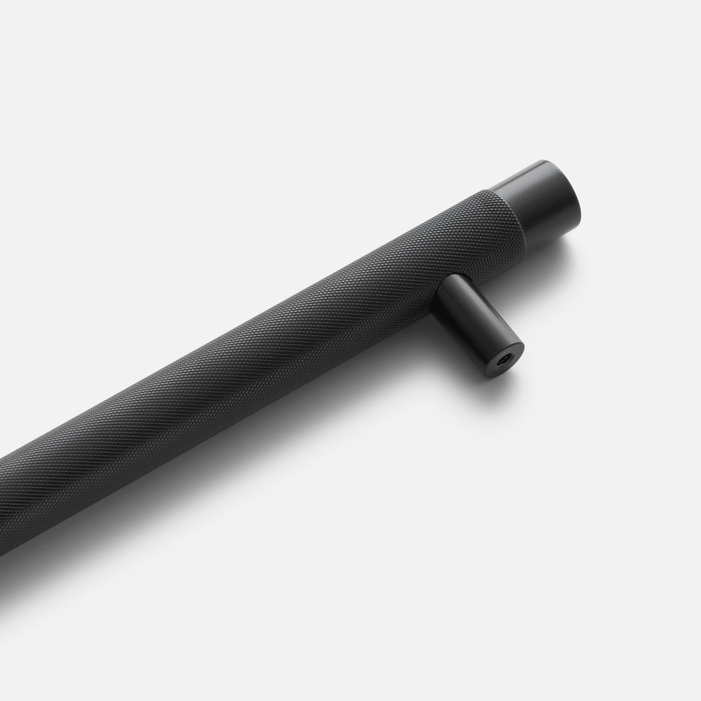 Angled view of black Knurled Appliance Pull showcasing its diamond-knurled grip and mounting post against a light background