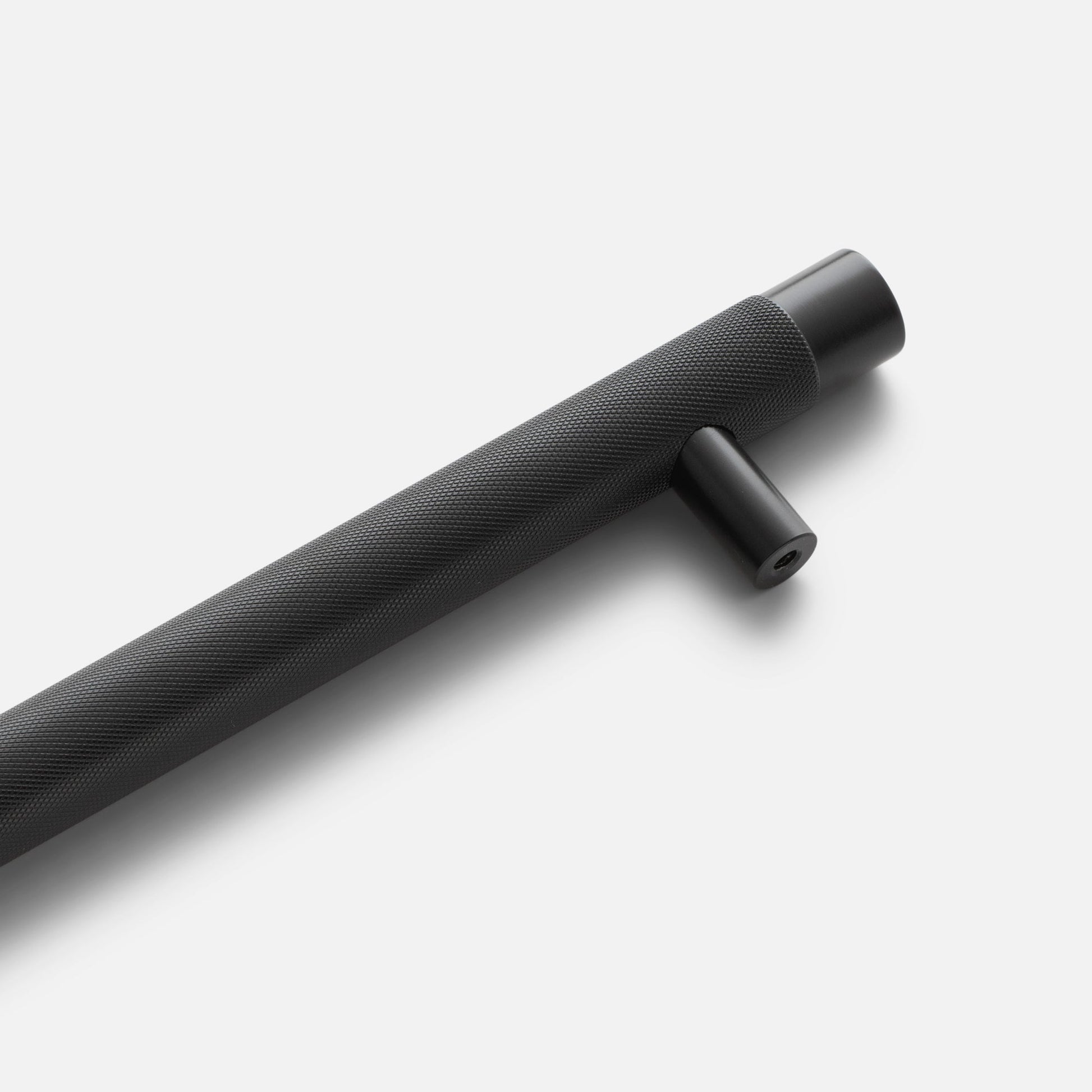 Angled view of black Knurled Appliance Pull showcasing its diamond-knurled grip and mounting post against a light background