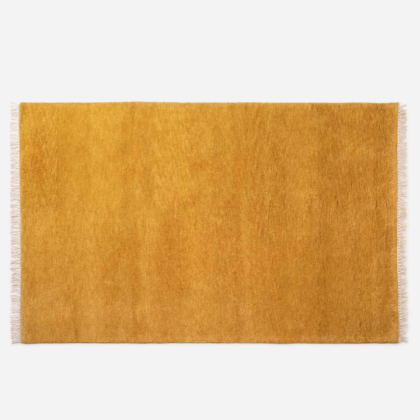 Top-down view of Mesa Wool Rug showing hand-loomed New Zealand wool cut pile and fringed edges on white background