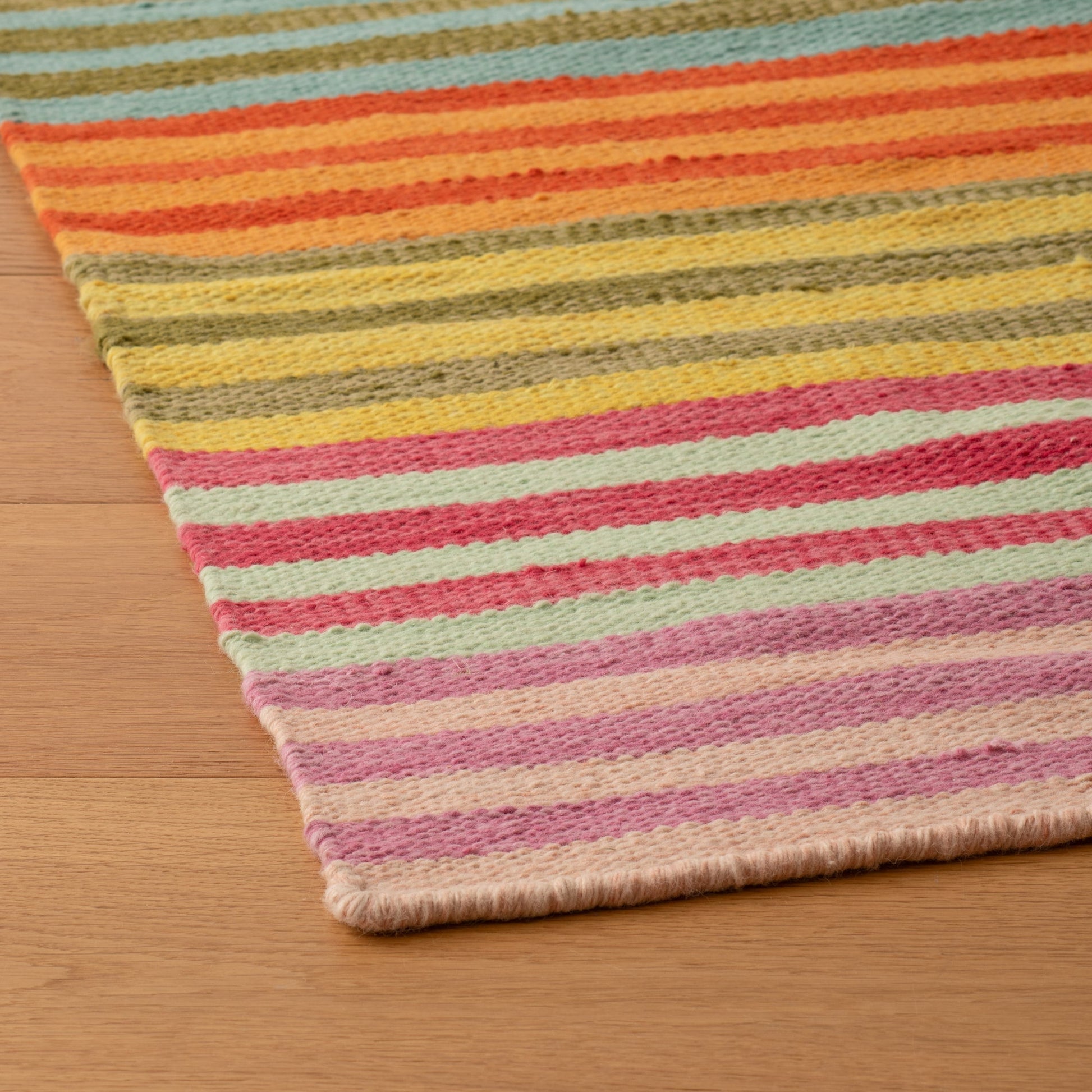 Close-up of Lisse Performance Rug showing multicolored flatweave stripes and low-profile edge on a hardwood floor