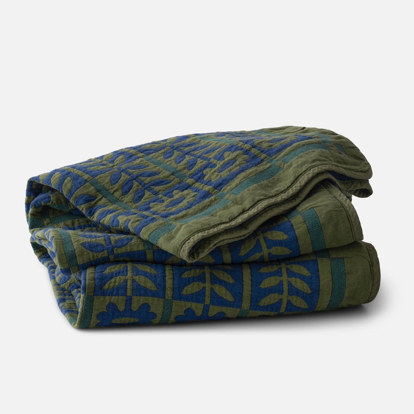 Folded Stillwater Floral Quilt showing green and blue floral block design and jacquard texture on white background
