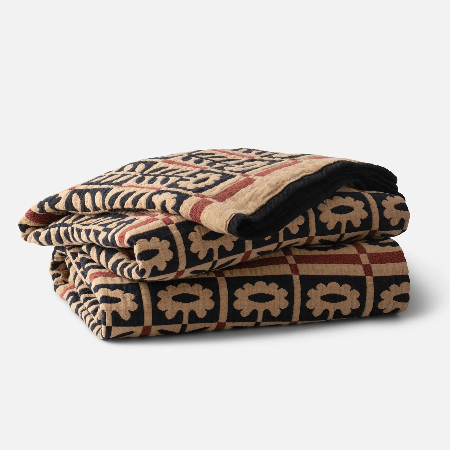 Folded Stillwater Floral Quilt showcasing mirrored floral motif, bold color-blocking, and jacquard woven cotton texture on white background