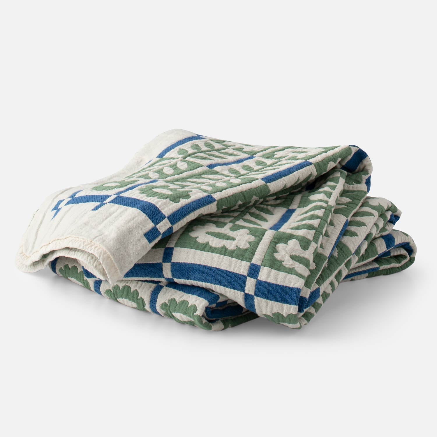 Folded Stillwater Floral Quilt showing green mirrored florals and blue grid with jacquard texture on white background