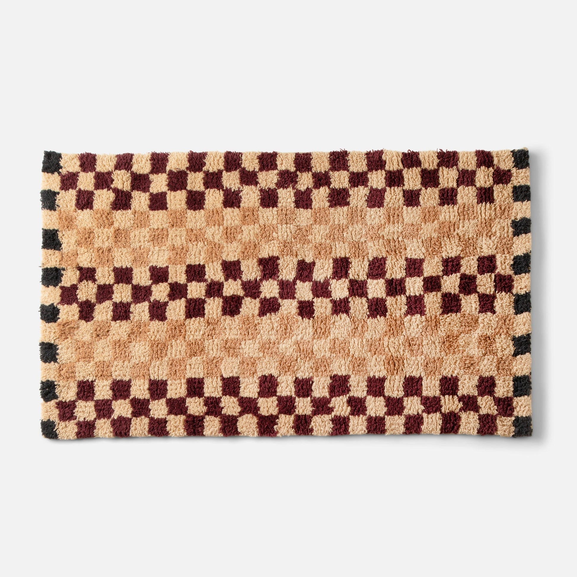 Top-edge close-up of Felix Shag Wool Rug showing butterscotch and burgundy checkerboard high-pile wool on white background