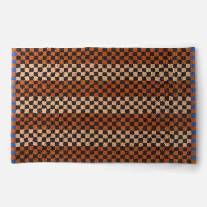 Top-down view of Schoolhouse x Clare V Felix shag wool rug showcasing checkerboard pattern in butterscotch, rust and black on white background