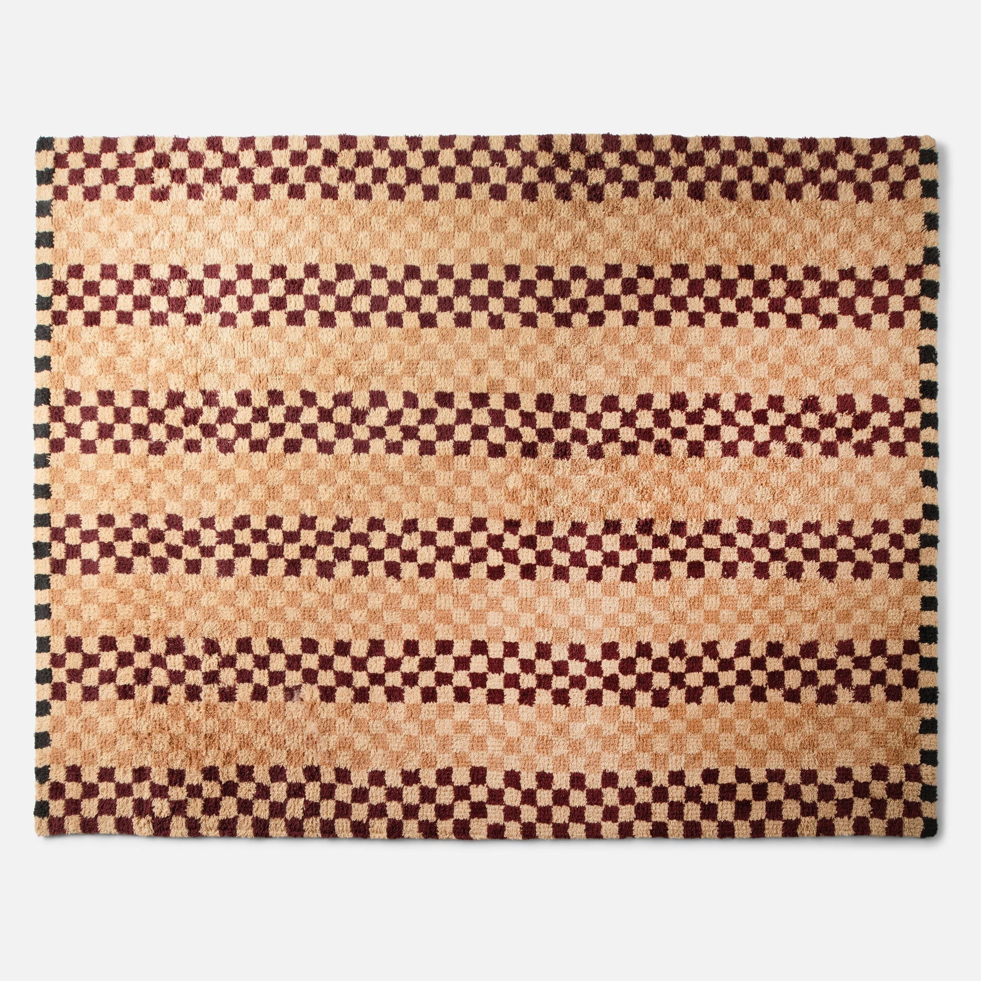 Top view of Felix Shag Wool Rug showcasing butterscotch and raisin checkerboard stripes and shag wool texture on white background