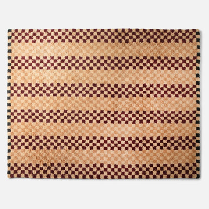 Top view of Felix Shag Wool Rug showcasing butterscotch and raisin checkerboard stripes and shag wool texture on white background