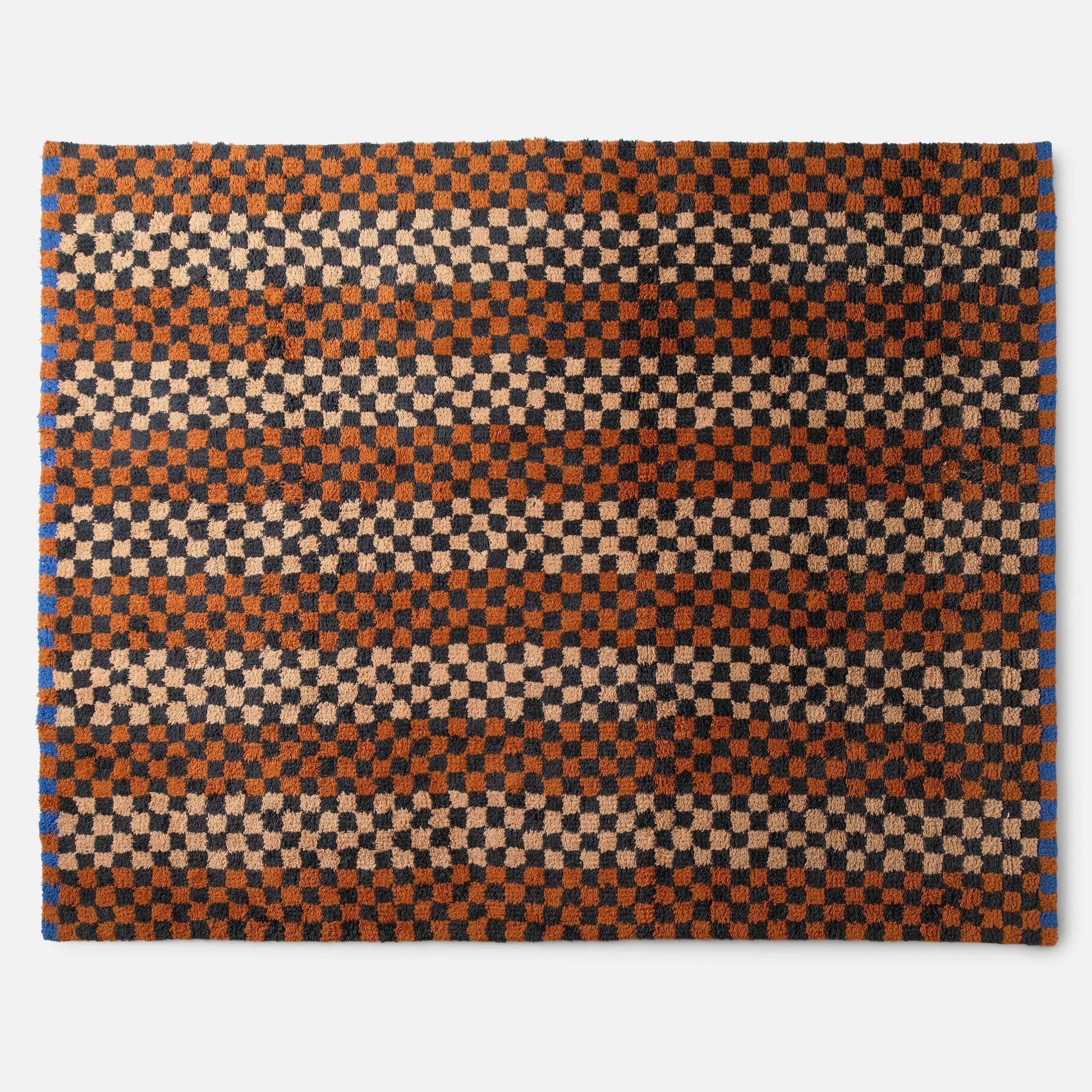 Top-edge view of Felix shag wool rug showcasing high-pile checkerboard in butterscotch, charcoal and cream on white
