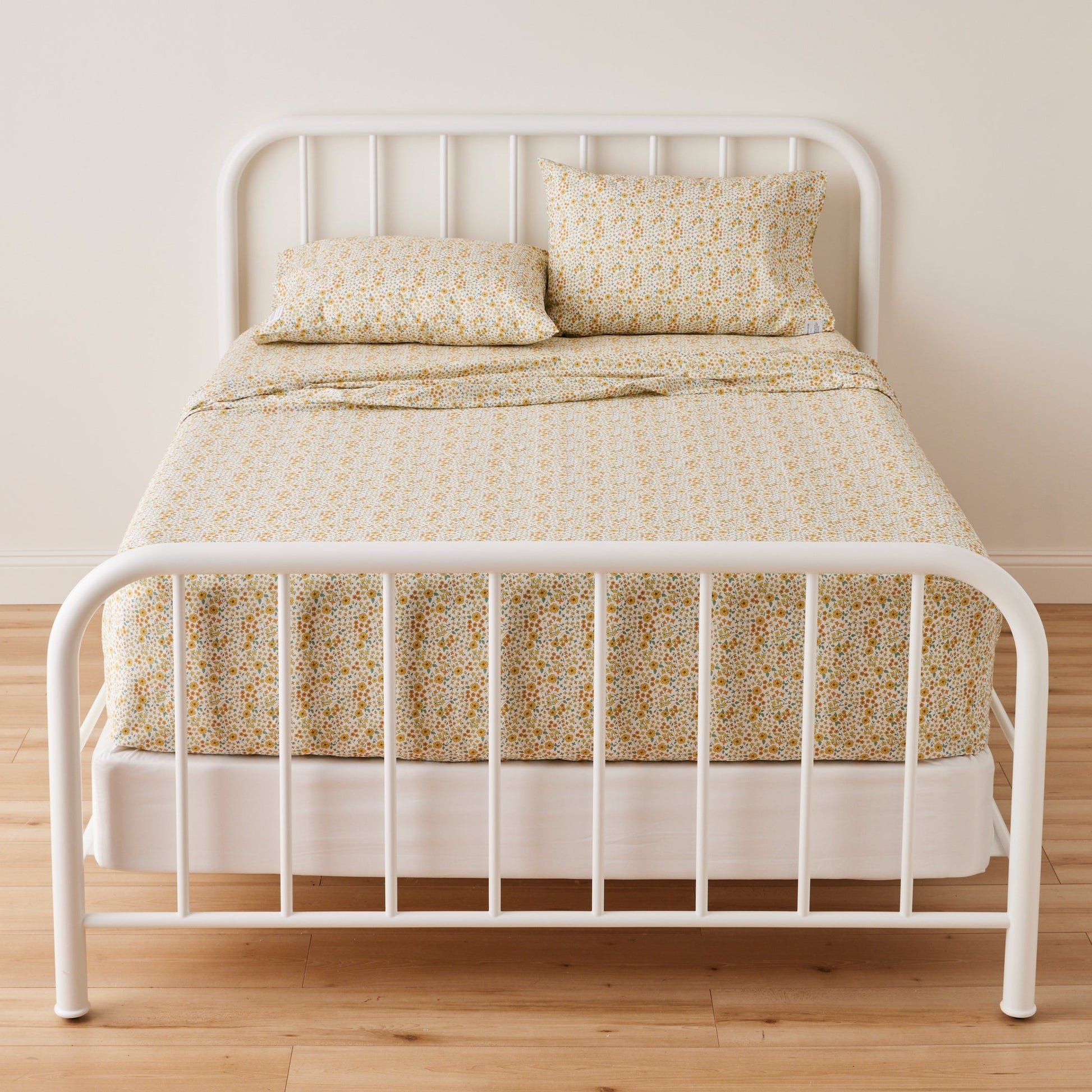 Front view of two Wallowa Floral Percale pillowcases showing chamomile floral print on percale with white metal bed frame