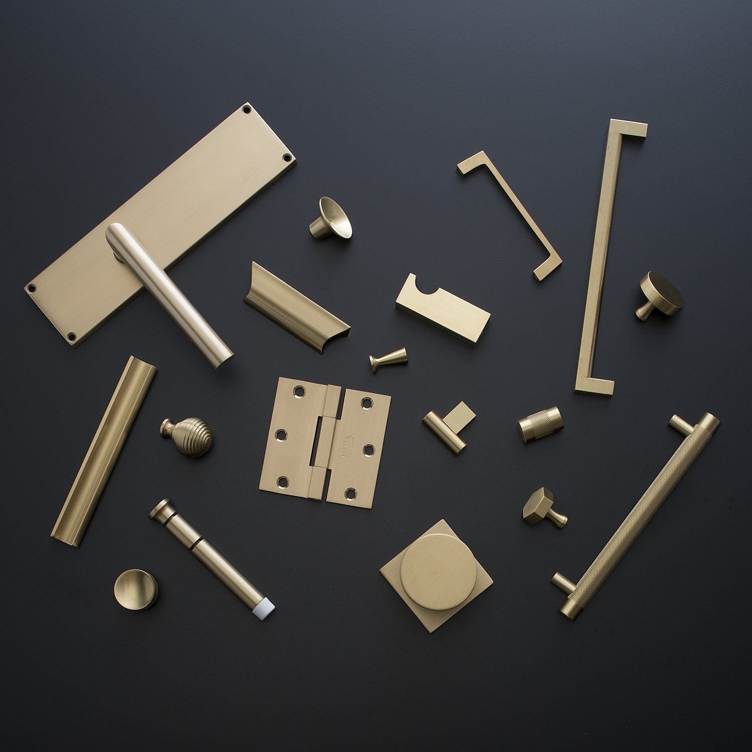 Top view of Knurled Pull and coordinating brass hardware arranged on a dark background