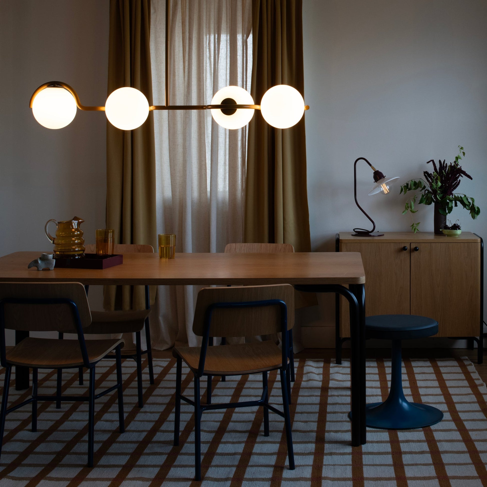 Cole Dining Chairs around a wooden dining table with globe pendant lights and curtains