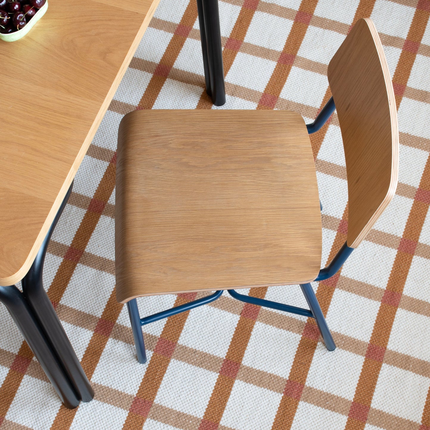Overhead view of Cole Dining Chair showing contoured oak veneer seat and backrest with powder-coated metal frame on a rug