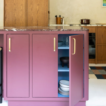 Lifestyle view of Cascade Appliance Pull showcasing vertical gold-tone pulls on pink cabinetry with one door open