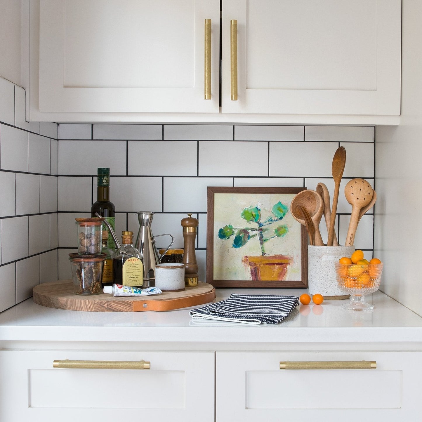 Front view of knurled appliance pulls showcasing cabinet installation in a bright white kitchen