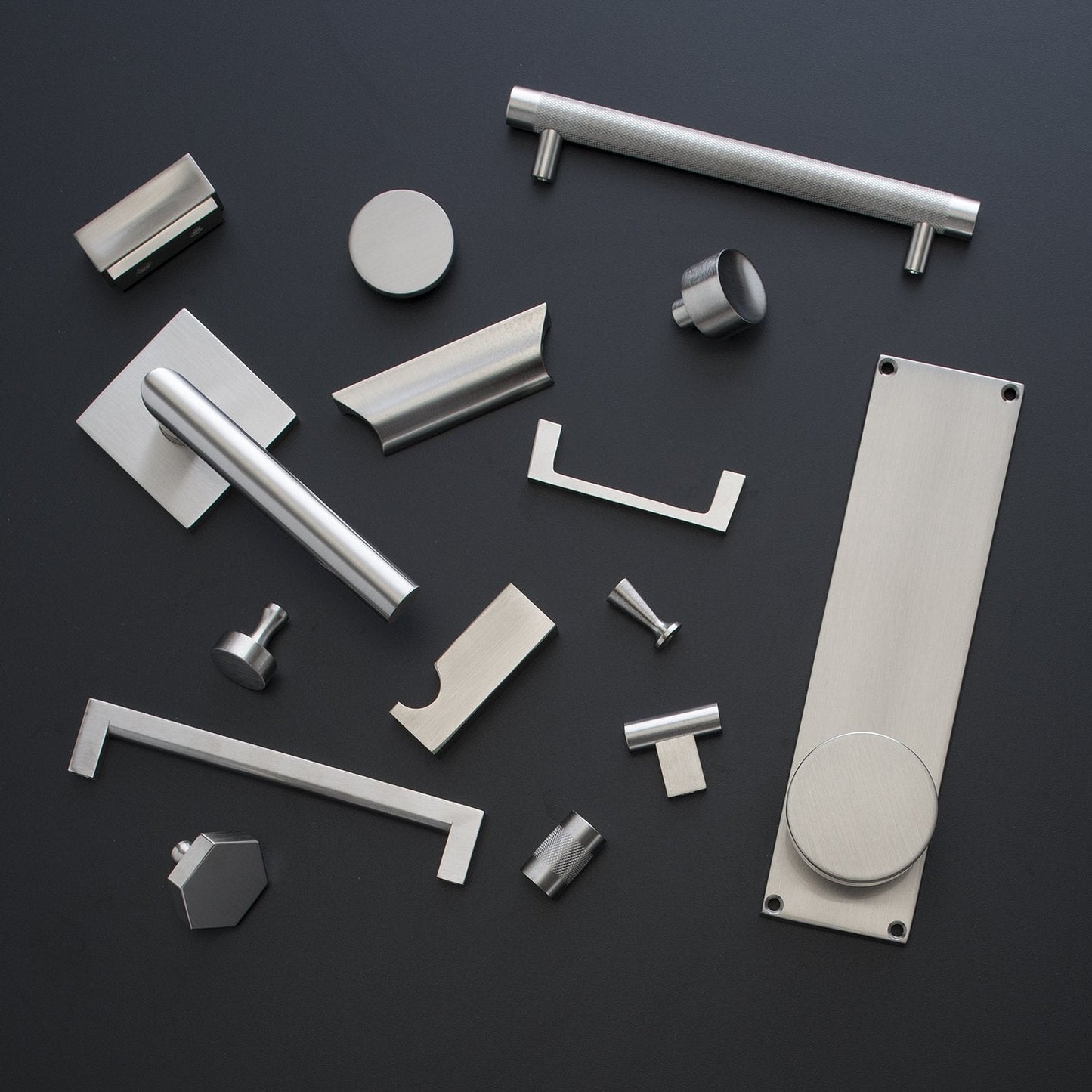 Top view of Knurled Pull showcasing its textured metal finish among assorted cabinet hardware on a dark background