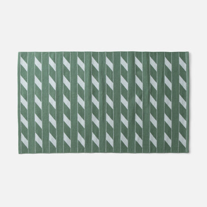 Flat-lay of Cotton Ladder flatweave rug showcasing green ladder stripe pattern and woven texture on white background